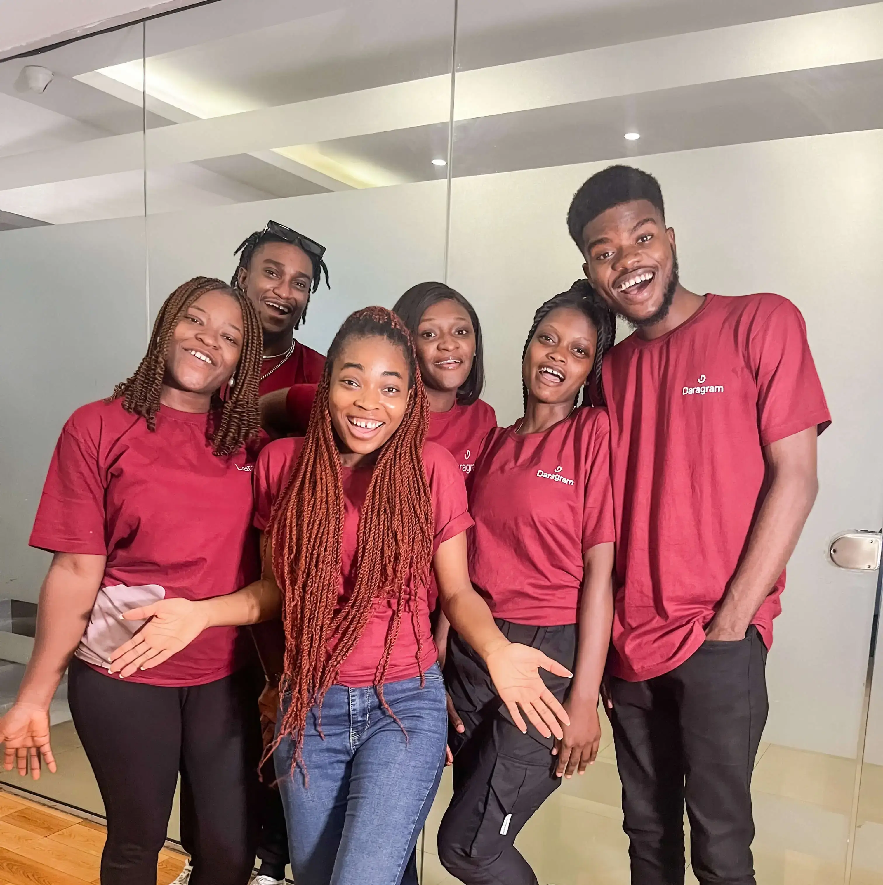 A group of Daragram's team members smiling happily dressed in the branded company shirt.